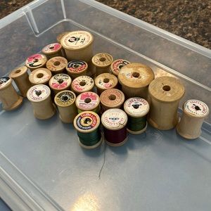 23 wooden spools, some have thread on them.